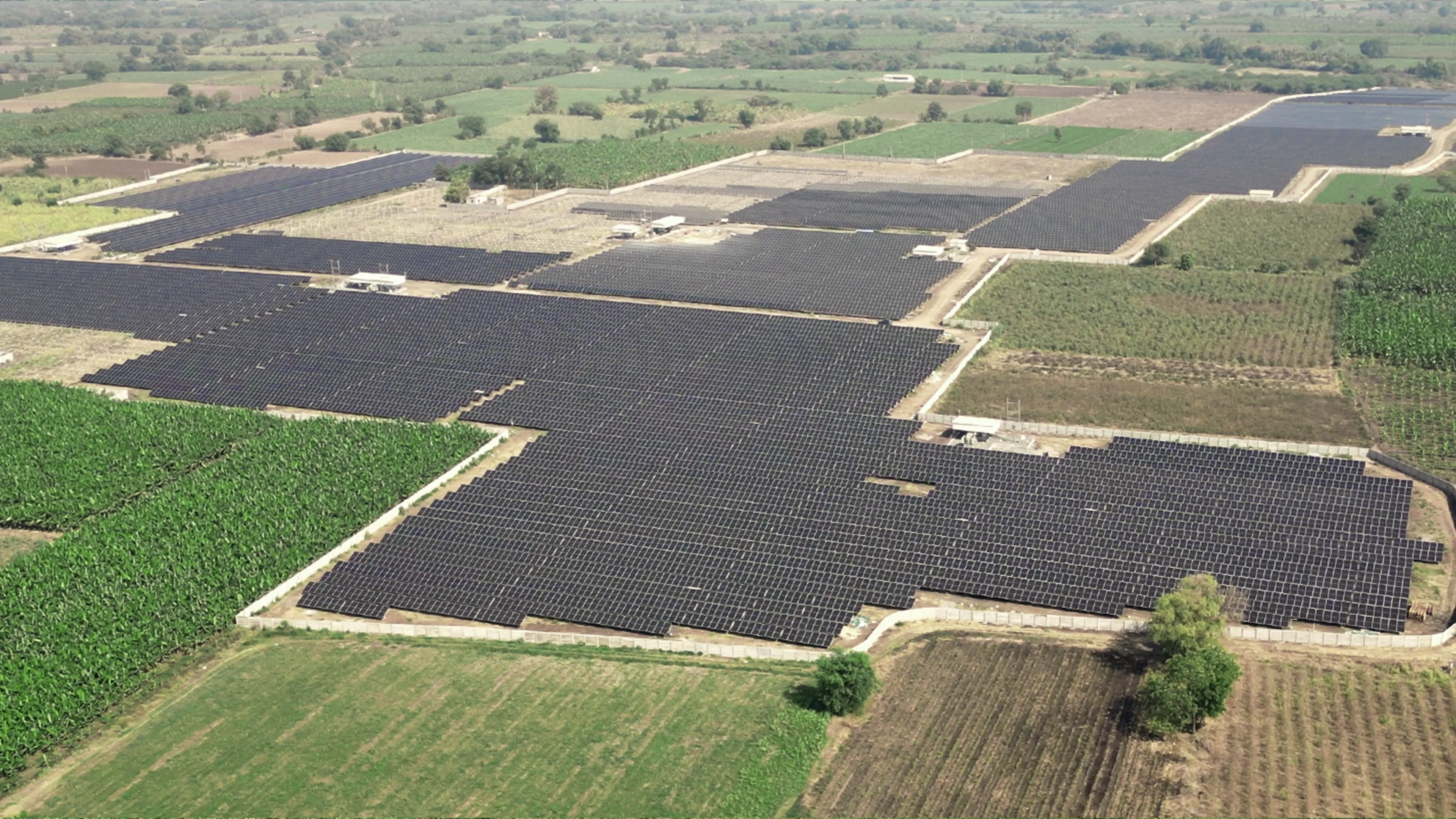 Ground-mounted solar panels at Rayzon Solar Park 3 in Asha surrounded by green landscapes.