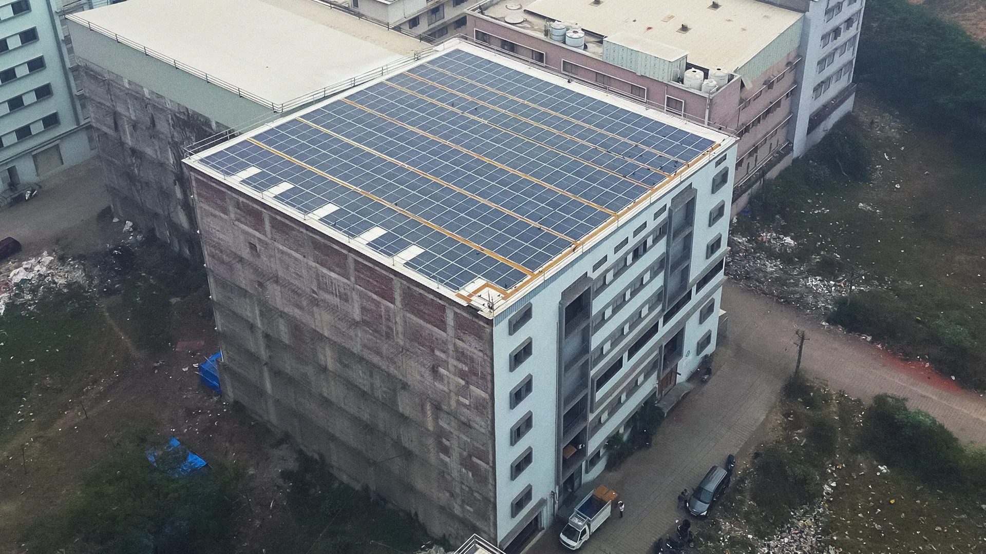 Extensive rooftop solar panel project at Ratnaveer Engineering Precision Ltd surrounded by farmland.